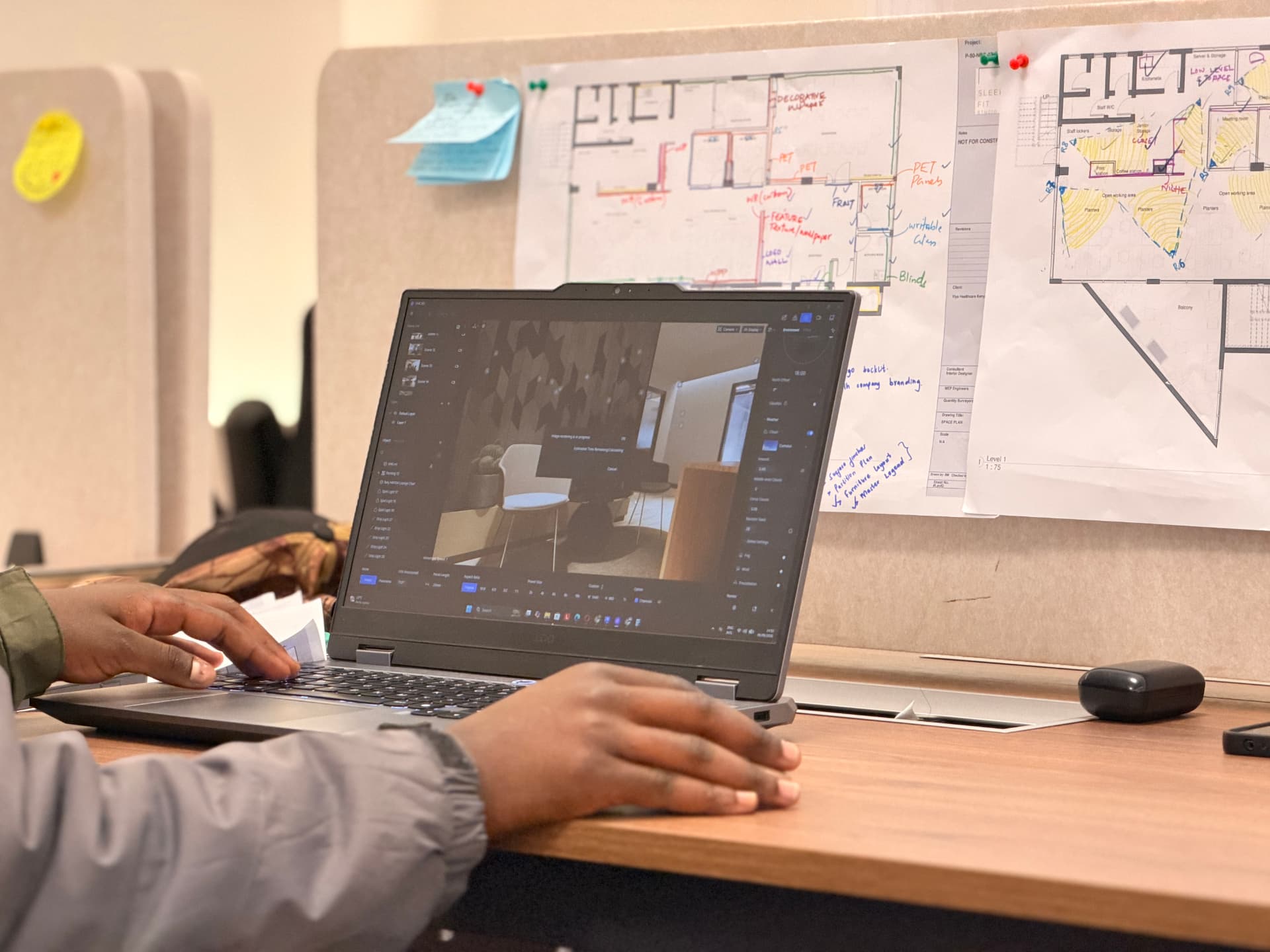Designer developing an interior model beside marked-up architectural plans