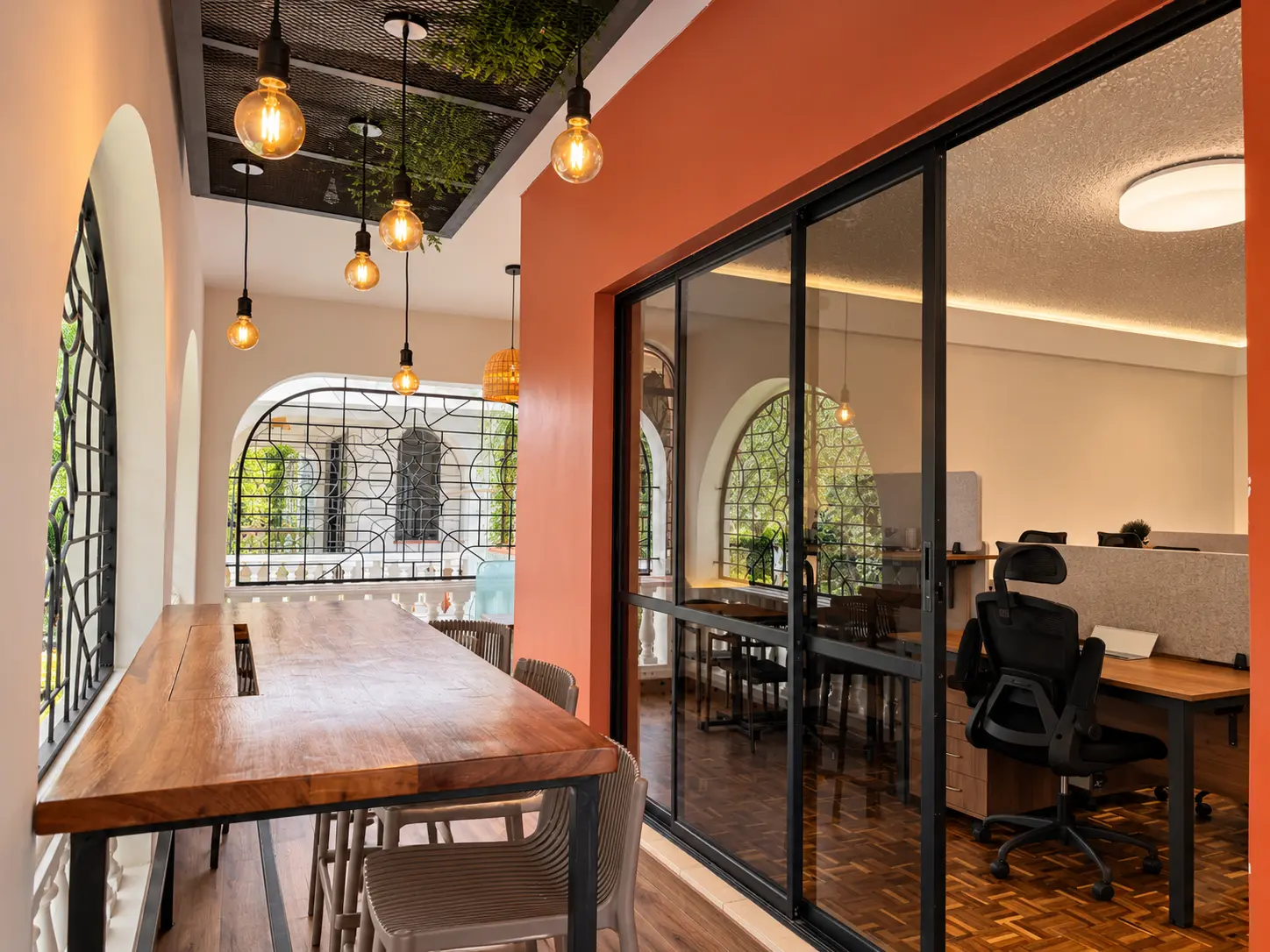 Long timber collaboration table on the studio balcony beneath pendant lights