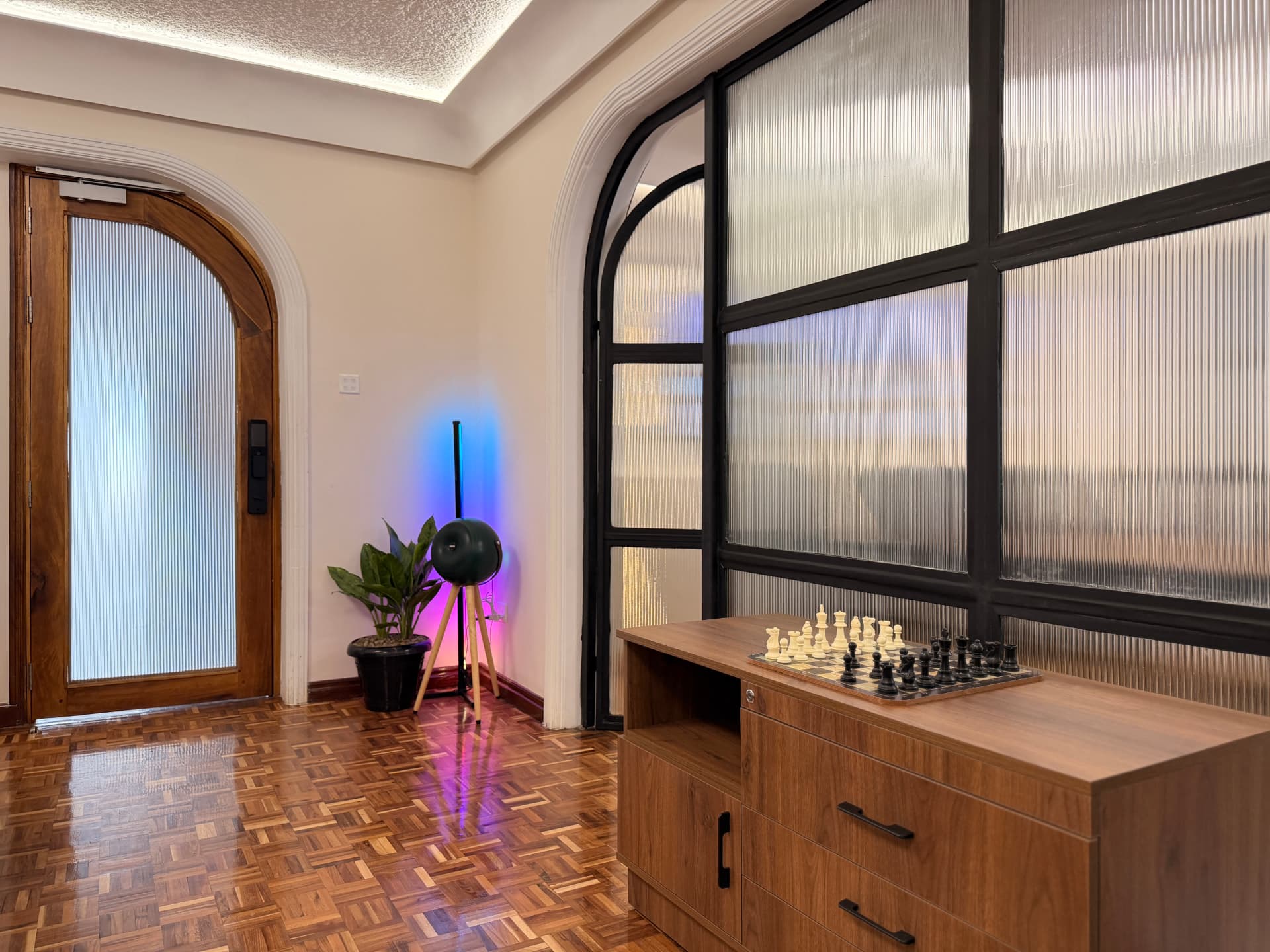 Chessboard on a walnut cabinet beside the studio's arched glass partition